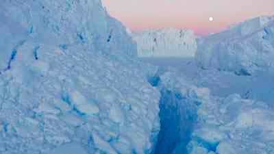 Chaos de glaces du glacier l'Astrolabe, sous un ciel rosé et le soleil bas de l'été austral