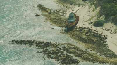 Survol d'un atoll en longueur, navire abandonné