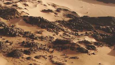 Route dans le désert et rochers qui émergent du sable