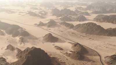 Route dans le désert et rochers qui émergent du sable