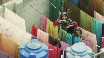 Des femmes font sécher la lessive colorée sur les toits de la ville