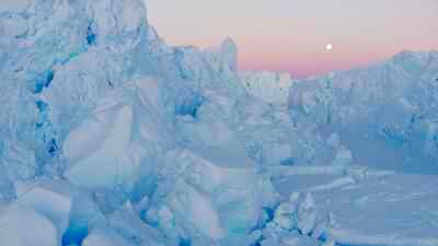 Chaos de glaces du glacier l'Astrolabe, sous un ciel rosé et le soleil bas de l'été austral