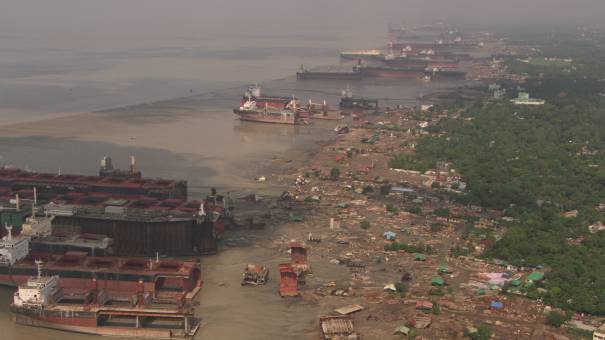 Carcasses de bateaux démantelés en bord de mer, ouvriers au travail