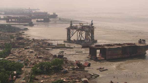 Carcasses de bateaux démantelés en bord de mer, ouvriers au travail