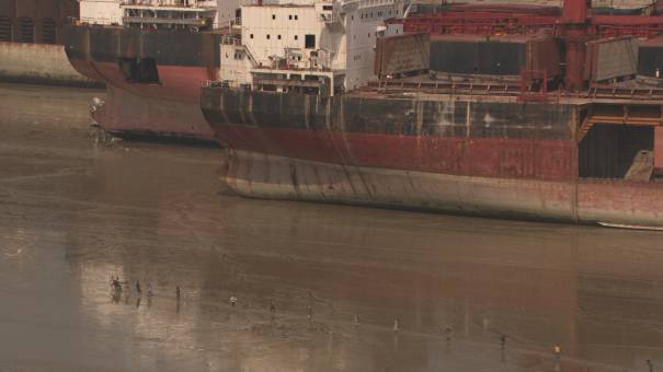 Carcasses de bateaux démantelés en bord de mer, ouvriers au travail