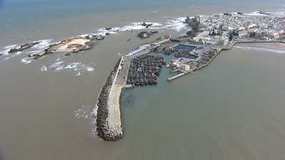 Survol du petit port de pêche, de la ville, d'une plage